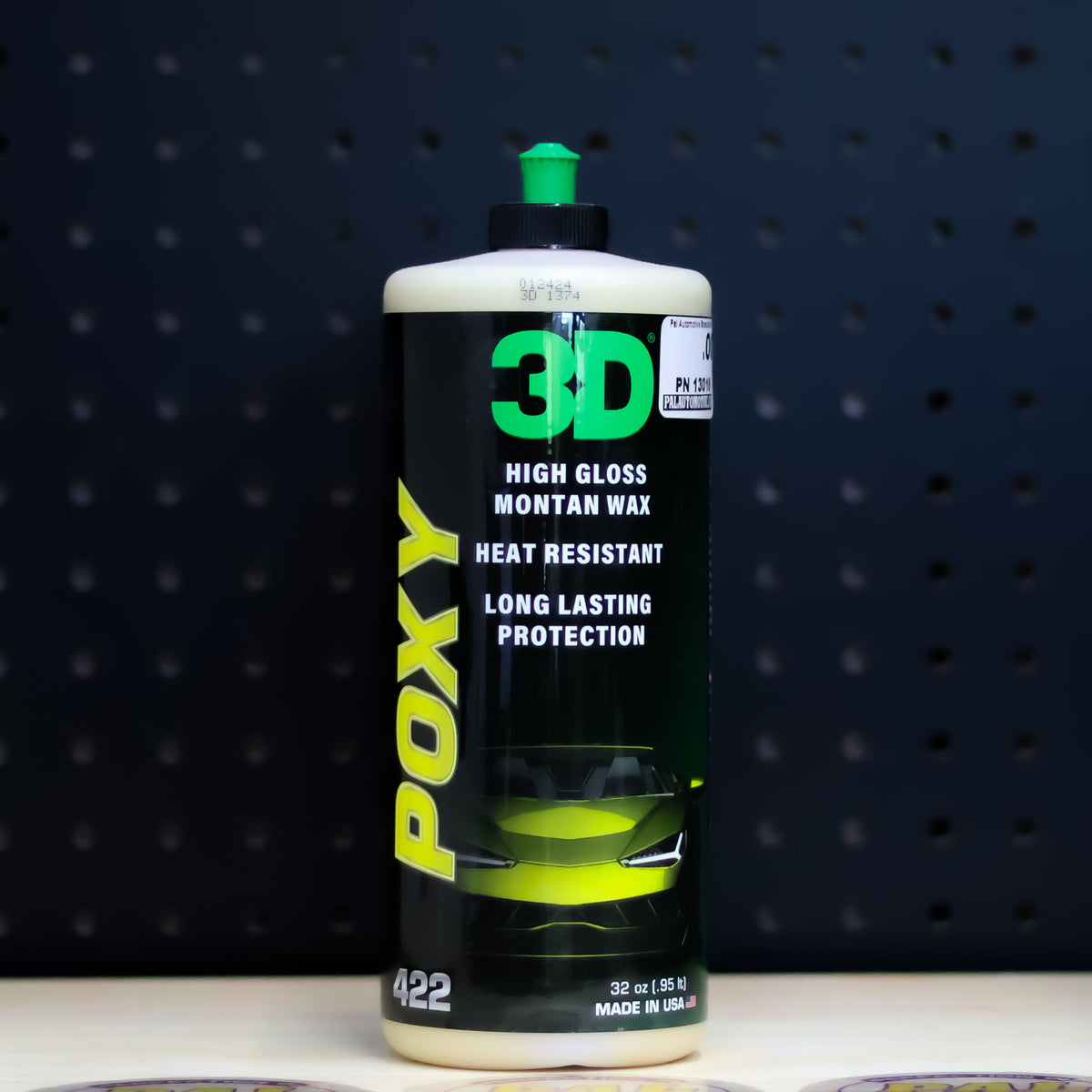 3D POXY 32 oz bottle, black label with yellow POXY lettering and a green cap, on a bench in front of a dark pegboard