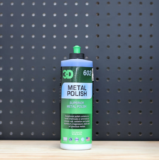 3D Metal Polish pint bottle, white and green label with a green cap, standing on a bench in front of a dark pegboard