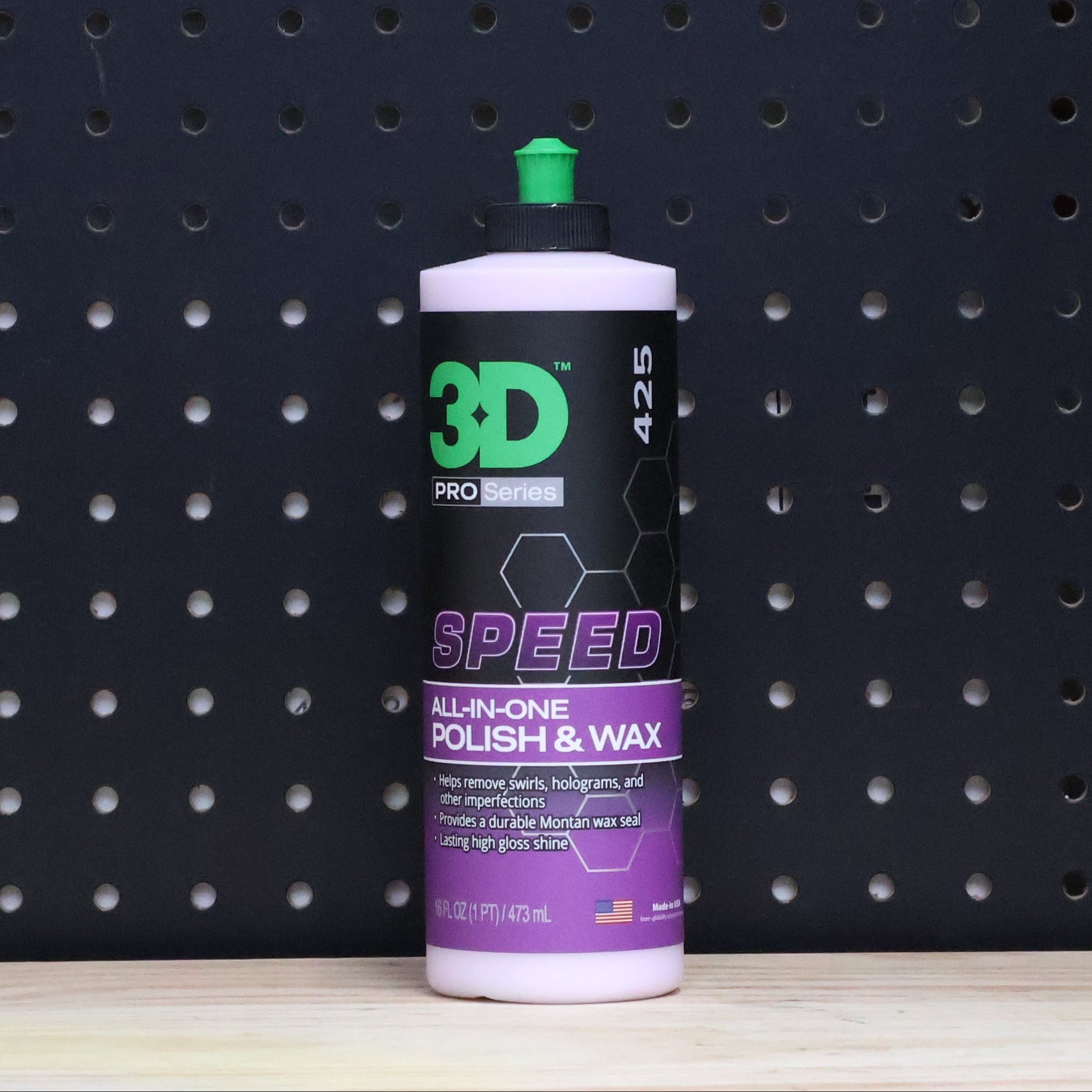 3D SPEED 16 oz bottle, purple and black all in one polish and wax label with a green cap, against a dark pegboard wall