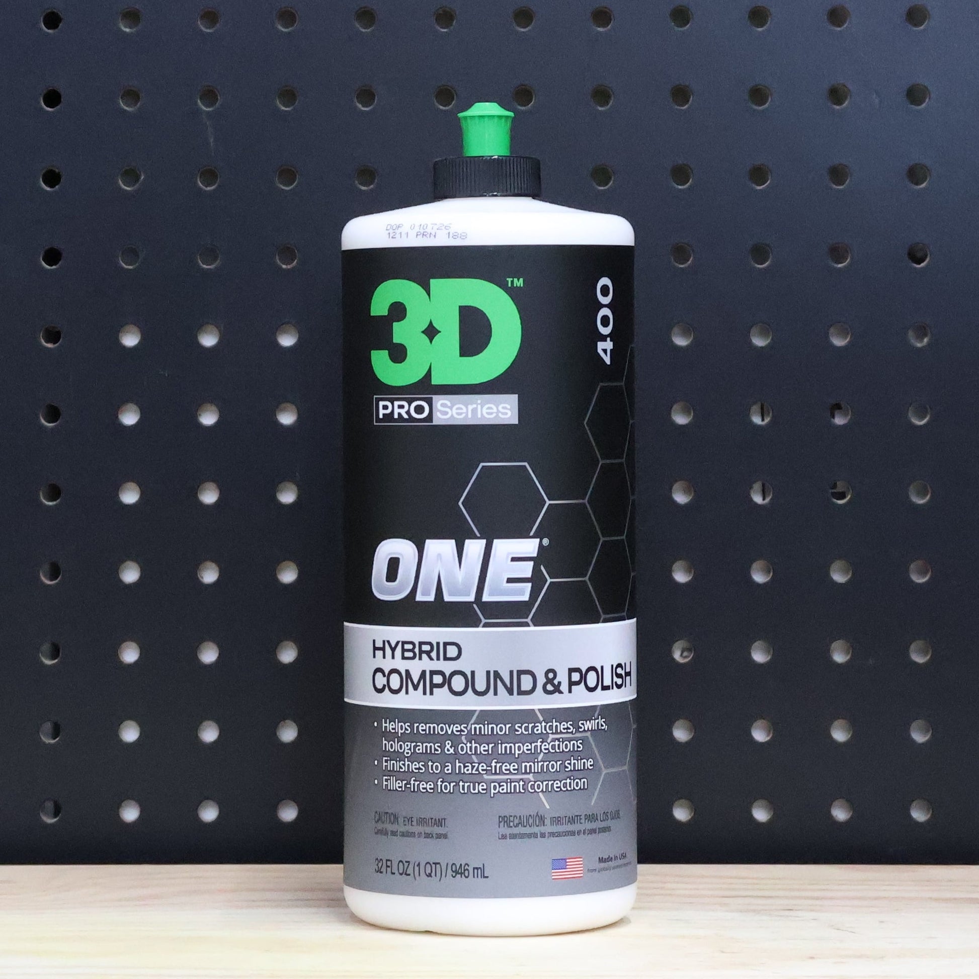 3D ONE hybrid compound and polish 32 oz bottle, black label with green ONE lettering and a green cap, against a dark pegboard wall